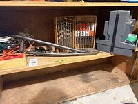 shelf view showing auger bit cases, pry bars, cords, organizer