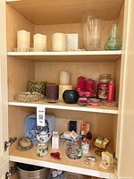 Wide view of cabinet shelves with candles, holders, soaps and small decor