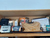 Overall shelf view showing travel bag, golf ball boxes, blanket, framed print