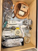 Drawer view of immersion blender, wooden bowl, utensils, mixer beaters, small jar