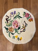 Needlepoint round rug with floral and butterfly motif on cream background