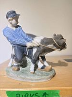 Front view of Royal Copenhagen porcelain figurine showing boy and calf
