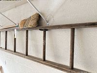 Side view of ladder hung on wall with broom resting on top