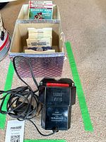 Box holding paper-sleeved View-Master reels alongside black Luma-View light attachment with cord