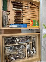 Drawer with mixed flatware, serving pieces, and utensil drawer above