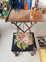 Top view of folding wooden TV tray table beside floral needlepoint footstool