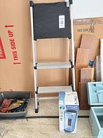 Werner 3-step ladder and boxed Bionaire fan side by side