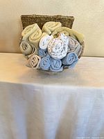 Front view showing small round basket filled with rolled washcloths and tall hamper basket behind