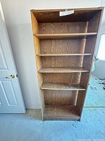 Front view of full-height wooden bookcase showing five shelves