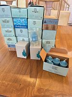 Front view of stacked PartyLite candle boxes, one box open showing blue candles, one glass votive holder on display