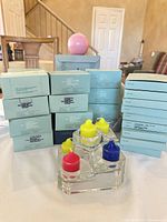 Stacked PartyLite candle boxes, glass holder with colored caps, pink round candle