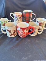 Eight mugs showing tartan, holiday, nautical and other designs