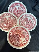 Four of the red transferware saucers showing pattern and border