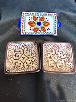 Top view showing three dipping bowls, two square patterned and one rectangular floral