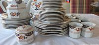 Full view of stacked plates, teapot, sugar bowl, cups