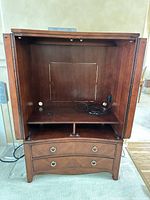 Armoire open showing interior shelf, cable openings, lower drawers