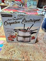 Front of boxed Nostalgia electric stainless steel fondue set