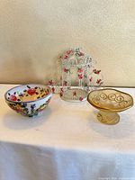 Full view of birdcage, ceramic bowl and glass candy dish on table