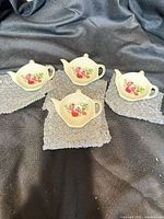 Four porcelain teapot-shaped tea bag rests displayed on bubble wrap