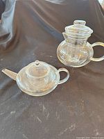 Overall lot view showing both clear glass tea vessels