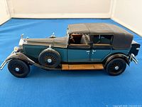 Passenger side view of die-cast Rolls-Royce model showing teal body, black roof, spare wheel, wood running board