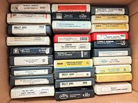 Overall view of open box showing four rows of 8-track cartridges with visible titles and wear