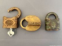 Front view of three brass padlocks showing maker stamps and attached keys on Corbin lock