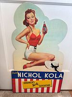 Full front view of Nichol Kola standee against wall