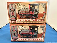 Front view of two identical Texaco 1910 Mack tanker coin bank boxes stacked