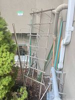 Trellis, tomato cages, stakes leaning against exterior wall