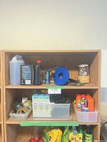 Shelf with assorted automotive fluids, torch, cord reel, cleaning supplies