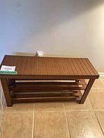 Front view of wooden bench showing top slats and two lower shelves