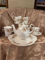 Full tea and coffee set displayed on fabric backdrop