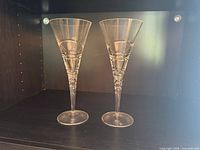 Two Royal Doulton crystal champagne flutes standing upright on shelf