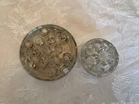 Top view of both glass flower frogs showing hole pattern and size difference