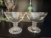 Two etched glass dessert bowls showing hobnail bases and etched pattern