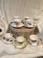 Seven floral bone china teacup and saucer sets displayed