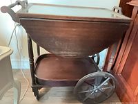 Full side view of mahogany tea cart showing wheels, lower shelf and body