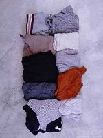 Stack of ten folded dresses showing variety of colours and textures