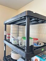 Shelf showing ceramic canisters, plastic containers with lids, glass jar and metal tray