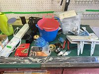 Group shot of entire lot on workbench showing watering can, diverter kit, bucket, light fixture, shelf brackets, pliers, tape, bulbs and more
