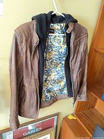 Full view of jacket hanging open showing exterior leather, hood, and lining