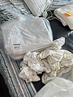 Bag of folded white sheets with maxsold tag and loose fitted sheet