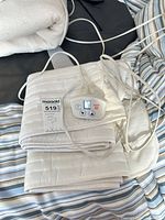 folded white quilted warmer pad with attached controller and cords