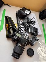 Top view of camera with accessories including chargers, manual, strap, battery packs, lens cap