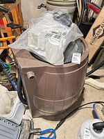 Front angled view of brown rain barrel with accessories bag on top