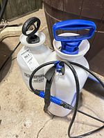 Two garden sprayers side by side showing pump handles, tanks, hoses