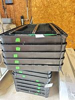 Stack of five black plastic shelves with side supports