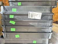 stack of black plastic shelves with lot sticker visible