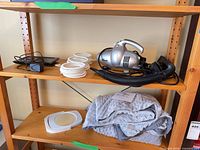 Shelf view showing digital frame, scarf hanger, Shark hand vac with hose, and makeup mirror plus folded weighted blanket